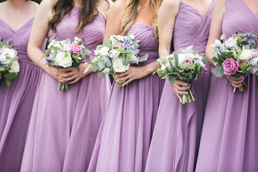 Close up image of bridesmaids wearing long purple bridesmaid dresses and holding their bouquets