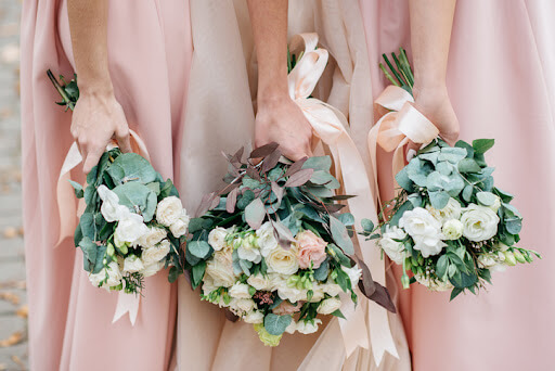 Close up image of three bridesmaid bouquets held by the bridesmaids who are wearing pink dresses