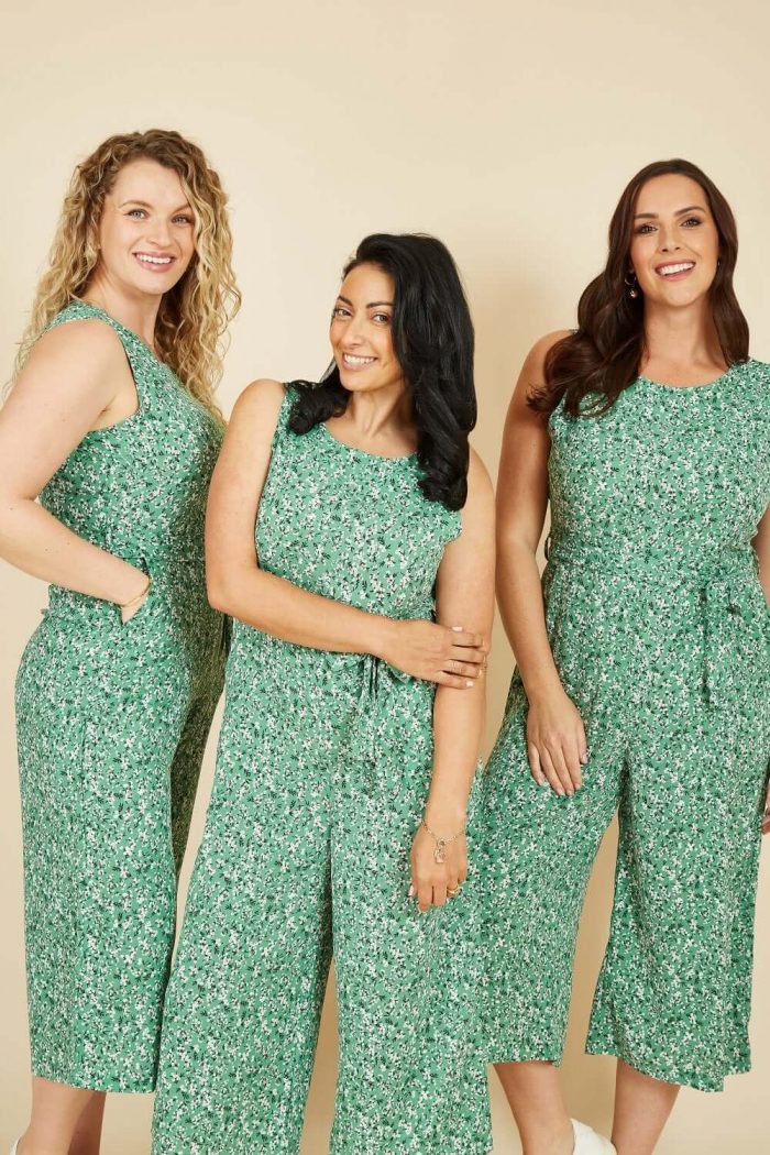 An image of three women wearing green sleeveless jumpsuits
