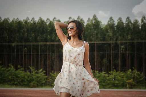 Image of a woman wearing a white floral summer dress and sunglasses