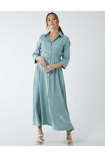 An image of a model wearing a blue satin belted shirt dress